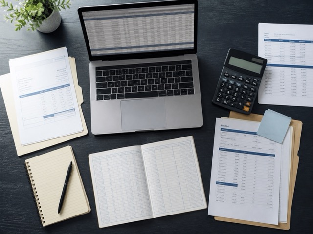 Accounting workspace with a laptop, calculator, and organized financial documents.